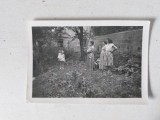 Fotografie veche anii 60, 3 femei si o fetita cu papusa in mana, intr-o curte, 9.5x6.5cm, alb-negru