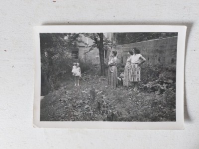 Fotografie veche anii 60, 3 femei si o fetita cu papusa in mana, intr-o curte, 9.5x6.5cm, alb-negru foto