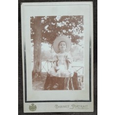 Fotografie pe carton, fetita la Slanic, asezata pe o bututuga, perioada interbelica
