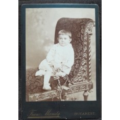 Fotografie pe carton, copil asezat intr-un jilt, inceput de secol XX