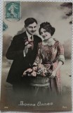 Fotografie tip Carte postala, barbat si femeie langa un cos cu flori, perioada interbelica