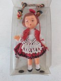 Papusica veche vintage, in cutie de plastic transparenta, snur tricolor, plastic cu haine textile, 8cm