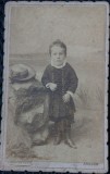 Fotografie tip CDV, fetita cu cizmulite si palarie langa ea, inceput de secol XX