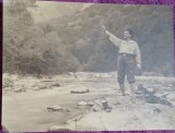 Fotografie, barbat in exursie la munte, pe malul unui parau, perioada interbelica