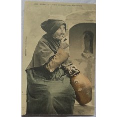 Carte postala, femeie varstnica care ia apa de la fantana, inceput de secol XX