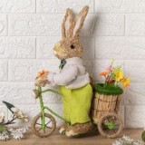 Iepure decorativ de Paște din iarbă, 42 cm, cu bicicletă și coș cu flori, CMCLASS