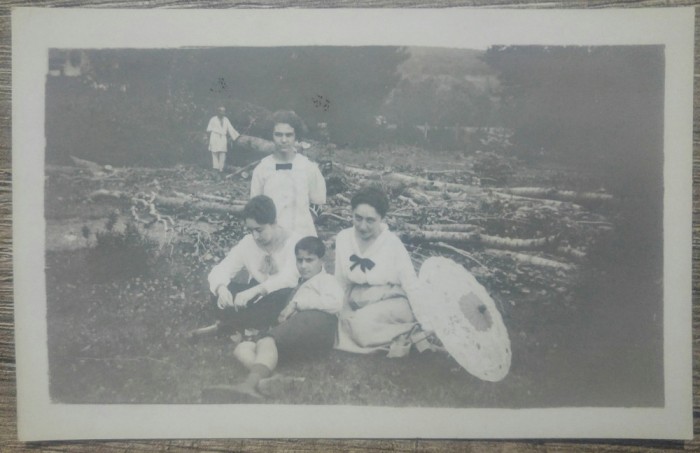 Grup de domnisoare, taran curatind copaci in fundal/ fotografie