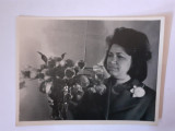 Fotografie dimensiune CP cu femeie l&acirc;ngă o vază cu flori