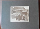 Fotografie pe carton, la tara in fata casei femei in costum popular, inceput de secol XX