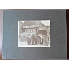 Fotografie pe carton, la tara in fata casei femei in costum popular, inceput de secol XX
