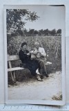 Fotografie interbelică tip carte poștală &ndash; cuplu pe bancă l&acirc;ngă lan de porumb &ndash; cca. 1930&ndash;1940