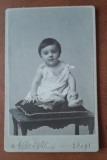 Fotografie tip CDV, copil mic pe bancheta, inceput de secol XX