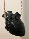 Geantă statement &icirc;n formă de inimă anatomică, cu finisaj negru lucios și lanț metalic auriu pentru purtare pe umăr.