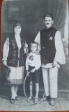 Fotografie tip carte postala, parinti cu copil in costume traditionale, perioada interbelica