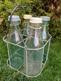 NI1074 4 sticle rom&acirc;nești cu capace din plastic, pentru lapte, cu coșul lor din s&acirc;rmă, perioada comunistă