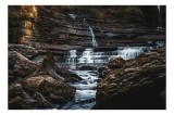 Tablou Canvas, "Cascada ascunsă printre st&acirc;nci tăcute", Cascadă, St&acirc;nci, Apă, Vegetație, Lumină, Curgere, Peisaj, Natură, R&acirc;u, Umbre, 39 x 26 cm, CMCL