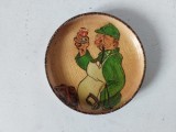 * Farfurie mica de lemn, vintage, pirogravata si pictata, barbat in verde, cu sort alb, care inchina un pahar, 9cm diametru