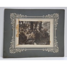 FOTOGRAFIE DE GRUP LA O MASA IN PADURE , MONOCROMA, PE SUPORT DIN CARTON , INCEPUTUL SECOLULUI XX , PREZINTA PETE