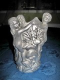 2624-Vaza argintie cu statuiete copii din material tare greu turnat gen rasina. Design cu 2 fetite si un baietel tinandu- se de mana.