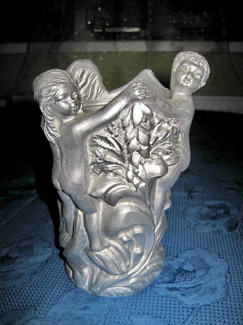 2624-Vaza argintie cu statuiete copii din material tare greu turnat gen rasina. Design cu 2 fetite si un baietel tinandu- se de mana.