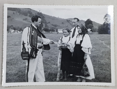 SERBARILE DE LA ABRUD , BARBAT IN COSTUM POPULAR IMPARTIND FOTOGRAFII CU FAMILIA REGALA UNOR LOCALNICI , FOTOGRAFIE MONOCROMA , DATATA PE VERSO 1938 foto