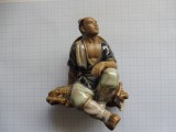 Bibelou vintage din portelan chinezesc. Taietor de lemne cu palarie, sezand.